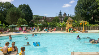 Familien entspannen sich und spielen im Freibad mit Wasserrutsche im Huttopia Beaulieu sur Dordogne.