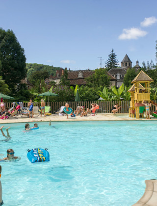 Familien entspannen sich und spielen im Freibad mit Wasserrutsche im Huttopia Beaulieu sur Dordogne.