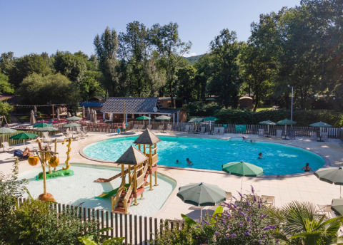 Piscina exterior y zona de juegos acuáticos infantiles con toboganes en Huttopia Beaulieu sur Dordogne, Francia.