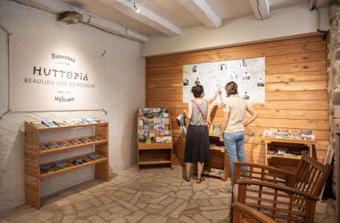 Dos personas mirando un mapa en la recepción de Huttopia Beaulieu sur Dordogne, un parque vacacional en Francia.