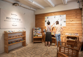 Twee personen bekijken een kaart in de receptie van Huttopia Beaulieu sur Dordogne vakantiepark, Frankrijk.