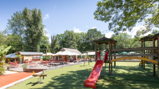 Spielplatz und Außenrestaurant im Huttopia Beaulieu sur Dordogne Ferienpark in Okzitanien, Frankreich.