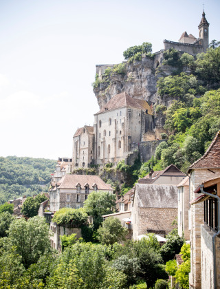 Mittelalterliche Gebäude und ein Kloster auf einem Felsen bei Beaulieu-sur-Dordogne, Occitanie, Frankreich.