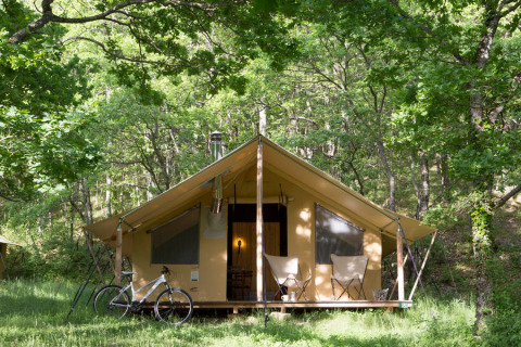 Tienda Trappeur tipo safari en Huttopia Lac de Serre Ponçon, Francia, rodeada de frondosos árboles.
