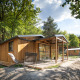 Træhytte ved navn Chalet Evasion i naturskønne omgivelser med terrasse og havemøbler under træer.