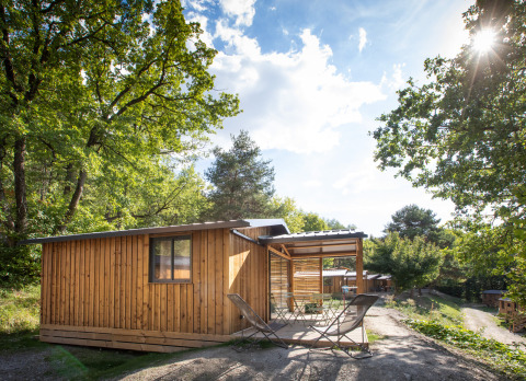 Houten blokhut Chalet Evasion met terras in de natuur bij Huttopia Lac de Serre Ponçon, Frankrijk.
