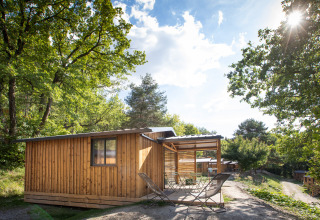 Houten blokhut Chalet Evasion met terras in de natuur bij Huttopia Lac de Serre Ponçon, Frankrijk.