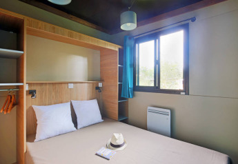 Moderne hytte-soveværelse i Chalet Evasion på Huttopia Lac de Serre Ponçon med dobbeltseng og vindue.