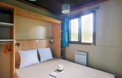 Dormitorio de cabaña moderna en Chalet Evasion, Huttopia Lac de Serre Ponçon, Francia, con cama y ventana.