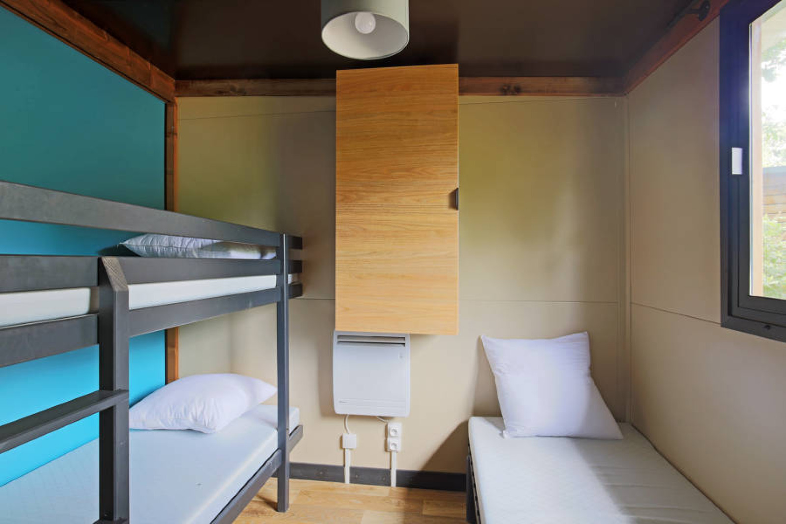Interieurfoto van Chalet Evasion glamping met stapelbed, eenpersoonsbed, houten kast en raam.