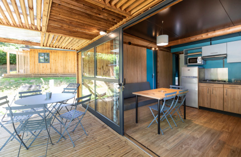 Licht Chalet Evasion glamping met terras buiten, eettafel en moderne keuken in een groene omgeving.