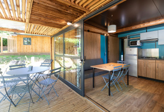 Luminoso Chalet Evasion glamping con terraza exterior, comedor y cocina moderna en plena naturaleza.
