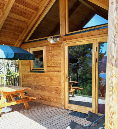 Terraza de madera y exterior del Montana chalet Vista en Huttopia Lac de Serre Ponçon, Francia.
