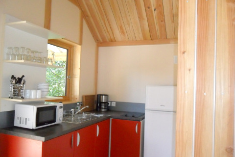Zona de cocina en Montana chalet Vista, Huttopia Lac de Serre Ponçon, Francia, con armarios rojos.