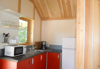 Keukenhoek in Montana chalet Vista te Huttopia Lac de Serre Ponçon, Frankrijk, met rode kastjes.