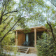 Chalet Portland, en træhytte omgivet af frodig skov, med terrasse og liggestole i naturlige omgivelser.