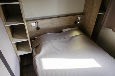 Moderne soveværelse på Chalet Portland, Huttopia Lac de Serre Ponçon, Frankrig med dobbeltseng og praktiske hylder.
