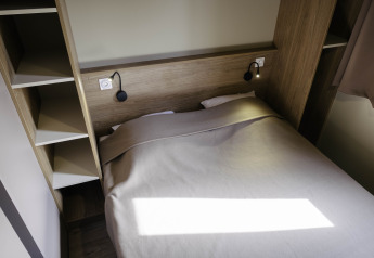 Moderne soveværelse på Chalet Portland, Huttopia Lac de Serre Ponçon, Frankrig med dobbeltseng og praktiske hylder.