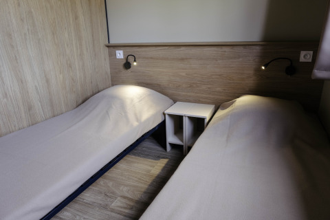 Twee eenpersoonsbedden in een eenvoudige houten kamer in Chalet Portland, Huttopia Lac de Serre Ponçon, Frankrijk.