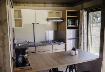 Cocina moderna en Chalet Portland de Huttopia Lac de Serre Ponçon, Francia, con estufa y refrigerador.