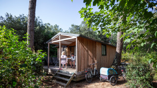 Twee mensen genieten op het terras van Chalet Evasion, een houten chalet omgeven door natuur.