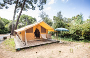 Tienda safari Bungalow Classic en Huttopia Chardons Bleus - Île de Ré en Francia, con terraza y sombrilla.