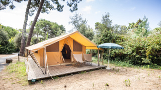 Tienda safari Bungalow Classic en Huttopia Chardons Bleus - Île de Ré en Francia, con terraza y sombrilla.