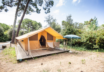 Tienda safari Bungalow Classic en Huttopia Chardons Bleus - Île de Ré en Francia, con terraza y sombrilla.