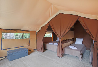 Intérieur d'une tente safari Bungalow Classic à Huttopia Vallouise en France avec deux lits simples.