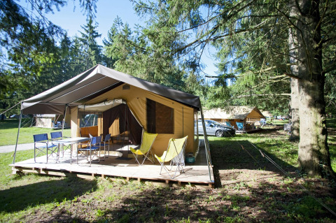 Tente safari Toile & bois tent Sweet à Huttopia Beaulieu sur Dordogne en France, entourée d’arbres.