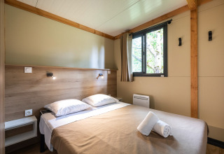 Slaapkamer in Mobile home Vancouver lodge met dubbel bed, raam en natuurlijk daglicht.
