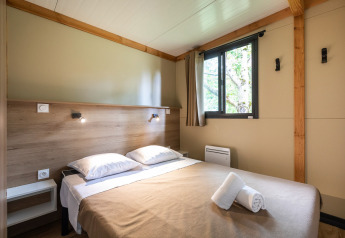 Dormitorio en Mobile home Vancouver lodge con cama doble, ventana y luz natural.
