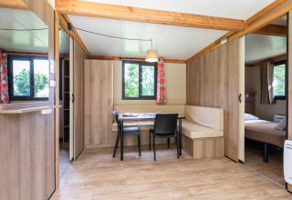Vista interior del Mobile home Vancouver en Huttopia La Plage Blanche, con zona de comedor y dormitorio.