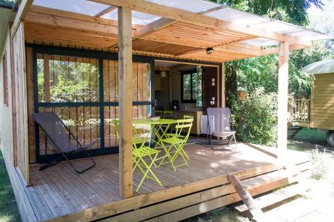 Træhytte med overdækket terrasse og havemøbler ved Chalet Evasion, Huttopia Beaulieu sur Dordogne, Frankrig.