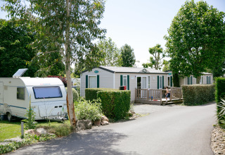 Camping Seasonova Saint Michel in Normandy, France, featuring mobile homes, a caravan, and lush greenery.