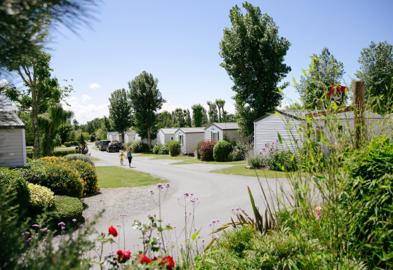 Case mobili tra piante e fiori nel Camping Seasonova Saint Michel, parco vacanze in Normandia, Francia.