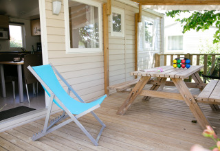 Houten terras met blauwe ligstoel en picknicktafel bij een stacaravan op Camping Seasonova Saint Michel, Normandië, Frankrijk.
