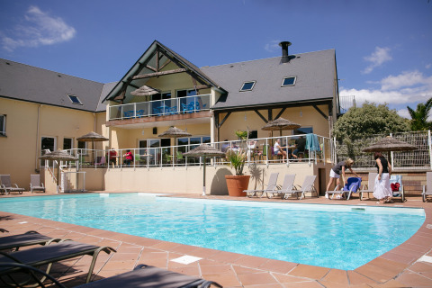 Piscina y zona de descanso en Camping Seasonova Saint Michel, un parque vacacional en Normandía, Francia.