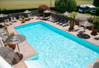 Udendørs swimmingpool med liggestole og parasoller på Camping Seasonova Saint Michel i Normandiet, Frankrig.
