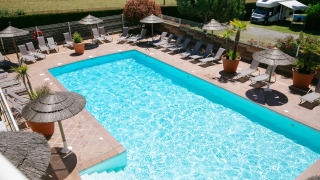 Piscina al aire libre con tumbonas y sombrillas en Camping Seasonova Saint Michel en Normandía, Francia.