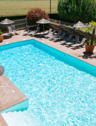 Piscina al aire libre con tumbonas y sombrillas en Camping Seasonova Saint Michel en Normandía, Francia.