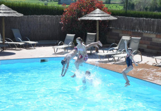 Children jumping into a swimming pool at Camping Seasonova Saint Michel, a holiday park in Normandy, France.