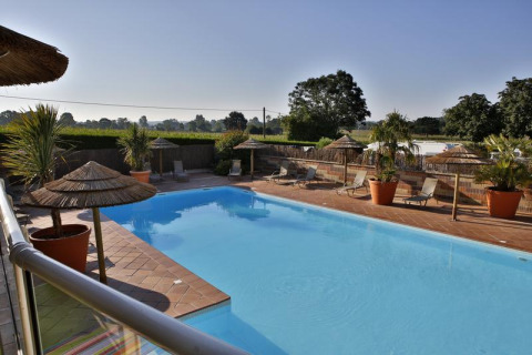Outdoor swimming pool with loungers and straw umbrellas at Camping Seasonova Saint Michel in Normandy, France.