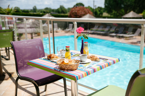 Desayuno al aire libre junto a la piscina en Camping Seasonova Saint Michel, parque vacacional en Normandía, Francia.
