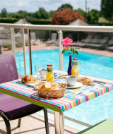 Desayuno al aire libre junto a la piscina en Camping Seasonova Saint Michel, parque vacacional en Normandía, Francia.