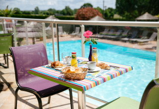 Colazione all'aperto a bordo piscina al Camping Seasonova Saint Michel, villaggio vacanze in Normandia, Francia.