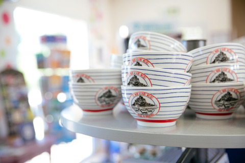 Ceramic bowls featuring Mont Saint-Michel design displayed on a shelf at Camping Seasonova Saint Michel, Normandy.