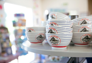 Ceramic bowls featuring Mont Saint-Michel design displayed on a shelf at Camping Seasonova Saint Michel, Normandy.