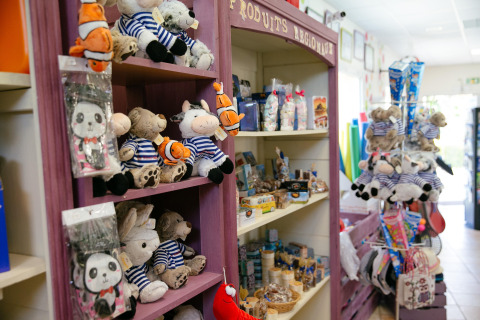 Tienda de juguetes y recuerdos en Camping Seasonova Saint Michel, Normandía, con peluches y dulces en estantes.