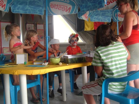 Kinderen knutselen onder parasols aan een tafel bij Camping Seasonova Saint Michel, Normandië, Frankrijk.